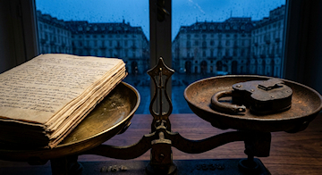 Volume aperto del codice di procedura penale italiano focalizzato sulla pagina dell'articolo 103 relativo alle garanzie di libertà del difensore, appoggiato su una scrivania in legno scuro.